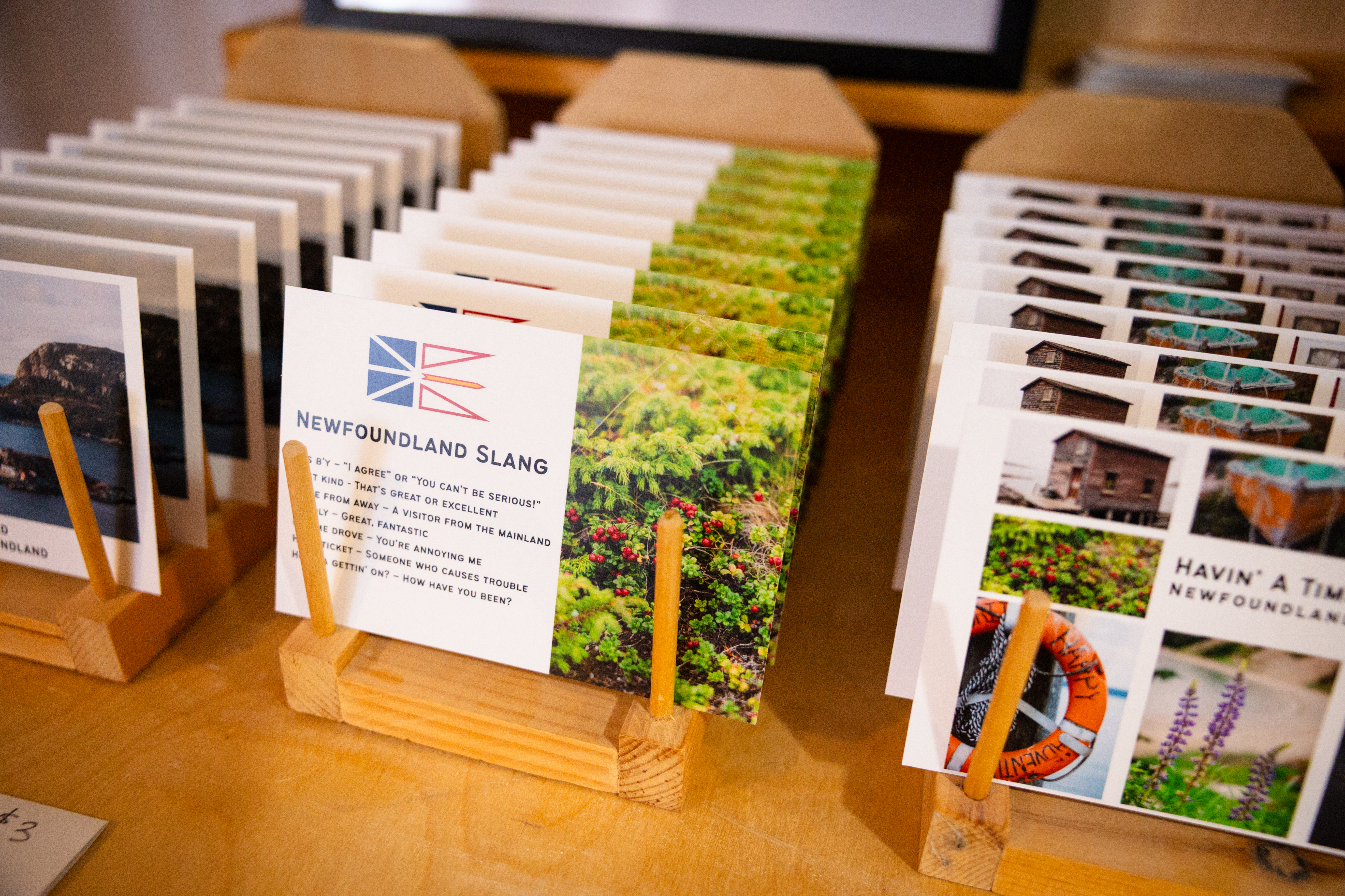 Photo showing a sample of newfoundland postcards featuring local photos and examples of slang.